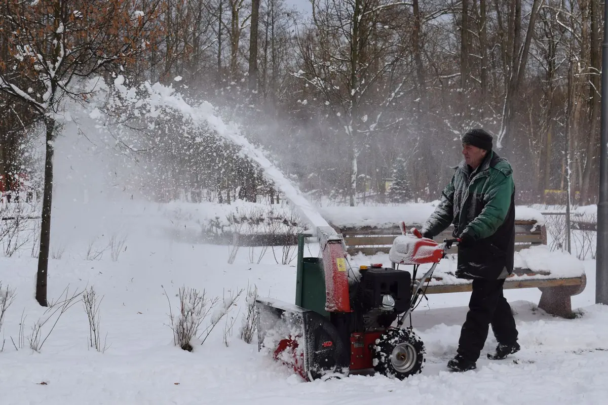 Snow blower throwing a stream of snow off a path